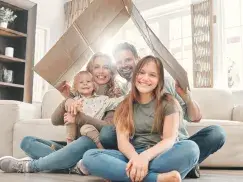 Eine glückliche Familie in einem lichtdurchfluteten Wohnzimmer.