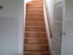 Gewendelte Holztreppe mit Geländer hinter weißer Innentür