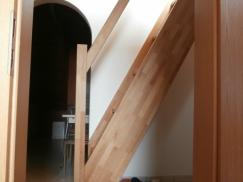Steile Holztreppe mit Geländer und unterhalb Kleiderhaken