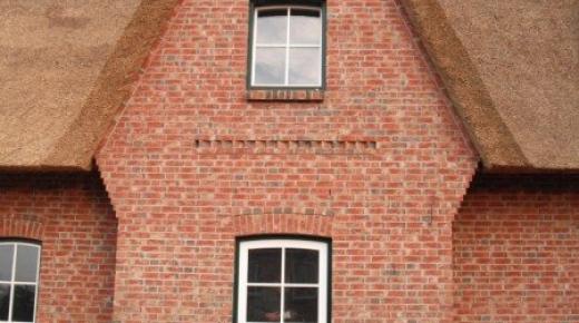 Hausansicht Einfamilienhaus mit Reetdach mit Haustür und Fenstern in grün/weiß