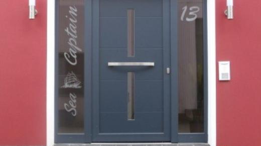 Haustür zu Apartment in blau mit zwei Lichtausschnitten und zwei Glas-Seitenteilen mit Schriftzug