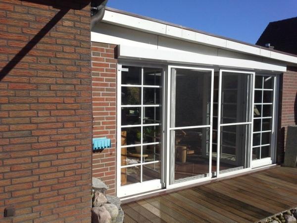 Doppelflügelige Terrassentür mit weißem Rahmen und Insektenschutz und zwei breiten Seitenteilen 