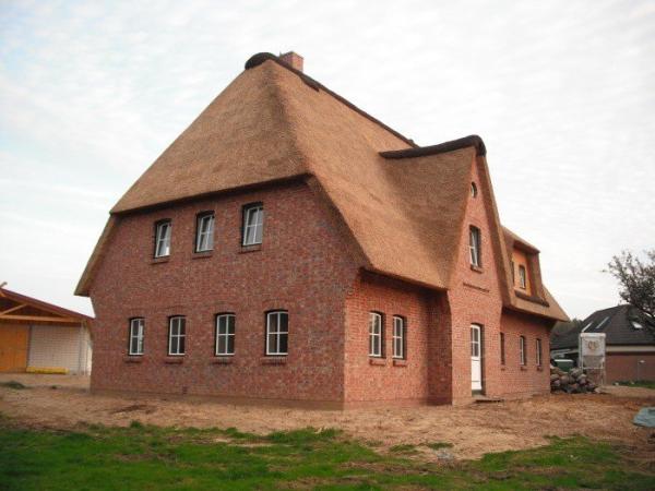 Hausansicht Einfamilienhaus mit Reetdach mit Haustür und Fenstern in grün/weiß 
