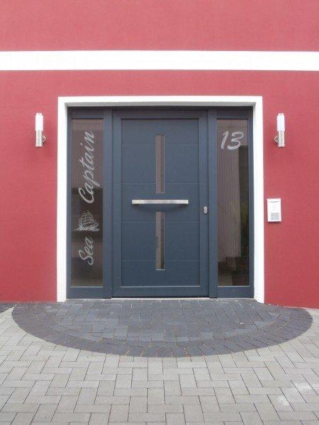 Haustür zu Apartment in blau mit zwei Lichtausschnitten und zwei Glas-Seitenteilen mit Schriftzug