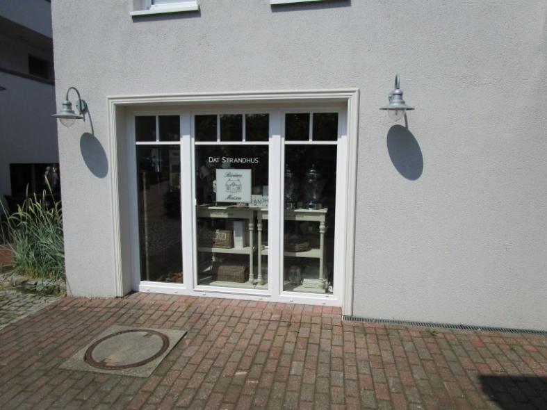 Hausansicht mit Geschäft im unteren Stock und weißen Fenstern und Türen