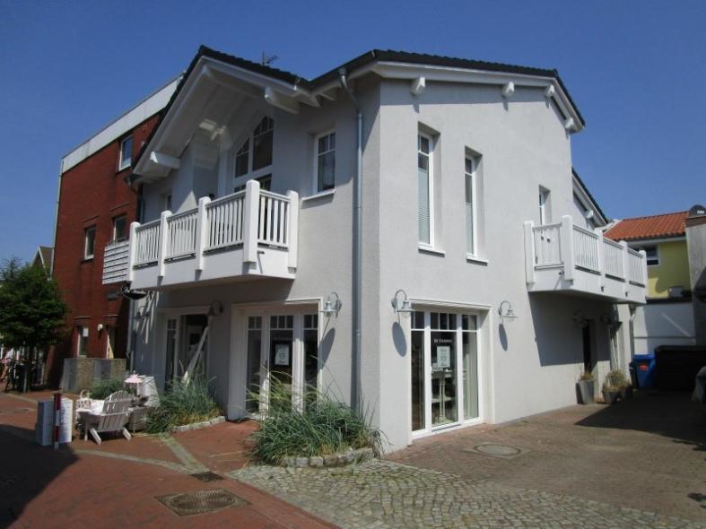 Hausansicht mit Geschäft im unteren Stock und weißen Fenstern und Türen