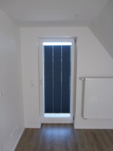 Plissee mit einem abdunkelnden blauen Stoff bei einer Terrassentür