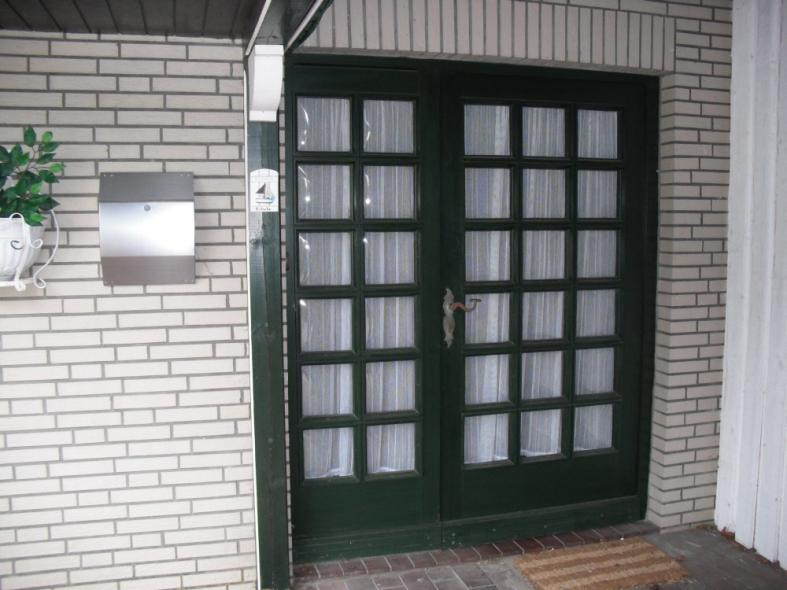 Doppelflügelige Haustür in grün mit vielen Lichtausschnitten geschlossen