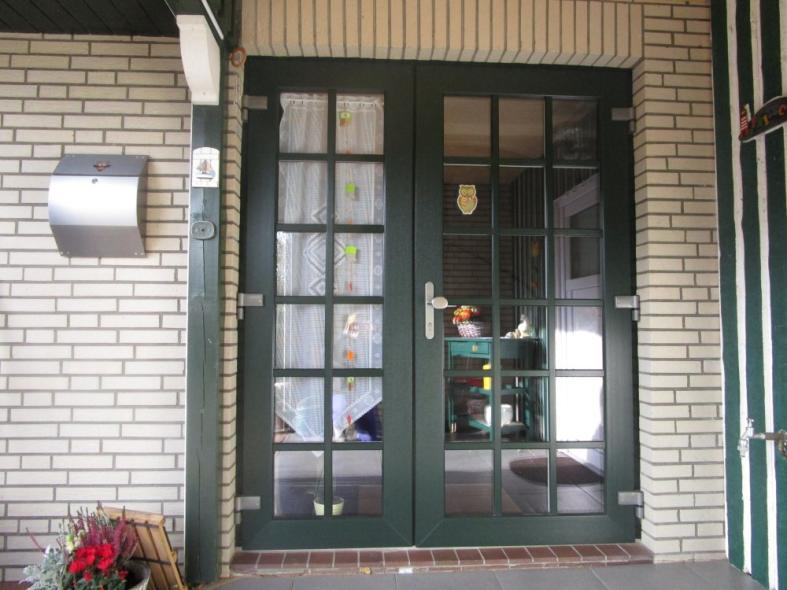 Doppelflügelige Haustür in grün mit vielen Lichtausschnitten geschlossen