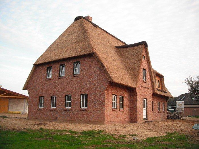 Hausansicht Einfamilienhaus mit Reetdach mit Haustür und Fenstern in grün/weiß