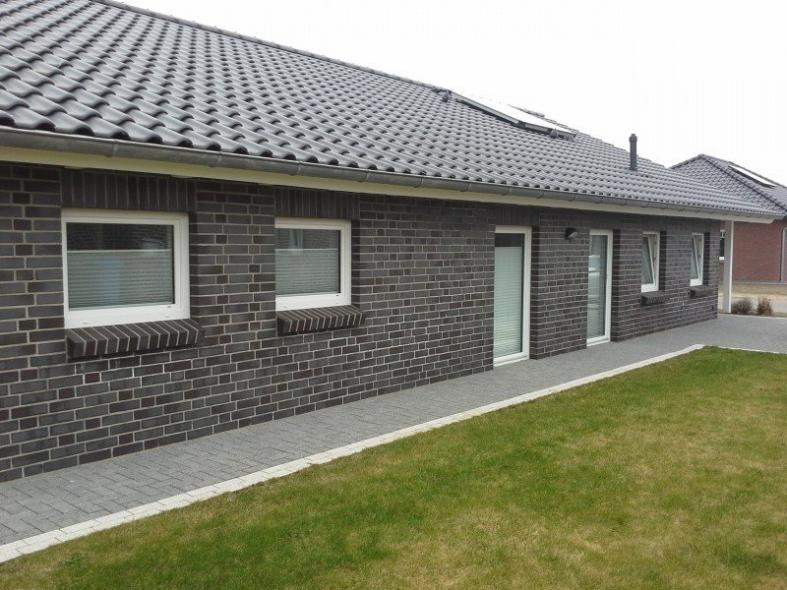 Hausansicht mit weißen Fenstern und Terrassentüren