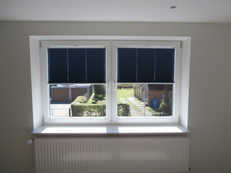 Innenansicht Fenster mit abdunkelnden Plissee aus blauem Stoff