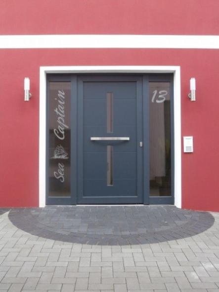 Haustür zu Apartment in blau mit zwei Lichtausschnitten und zwei Glas-Seitenteilen mit Schriftzug